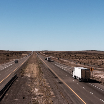 A highway in the southwestern United States with several cars and trucks traveling along it.